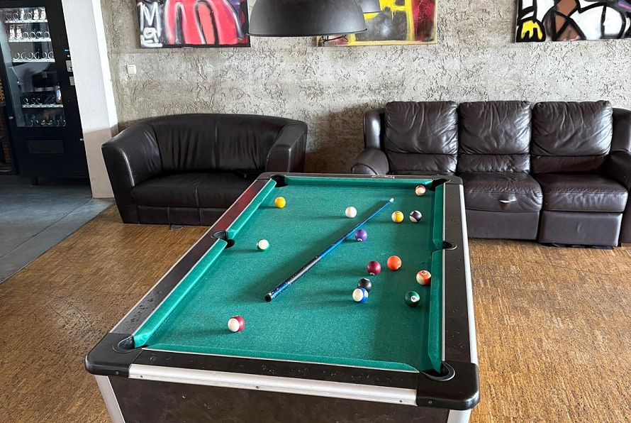 Ein Billardtisch im Jugendzentrum Kufstein, dahinter eine Ledercouch und die Räumlichkeiten der Einrichtung.